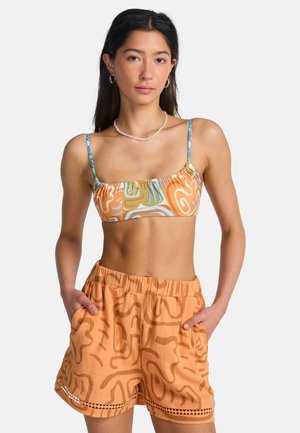 Bikinitop in blauw, oranje en beige met abstracte patronen; gecombineerd met oranje shorts met een gestructureerd ontwerp en kanten afwerking.