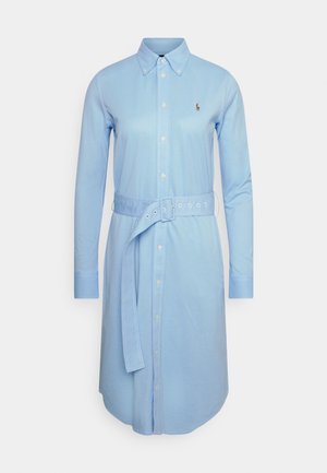 Robe-chemise bleu clair à manches longues, boutonnée sur le devant, col boutonné, ceinture en tissu avec trous, et petit logo brodé sur la poitrine.