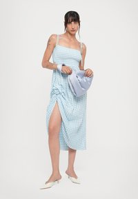 Sininen ruudullinen midi-mekko, jossa on spagettiolkain, sivureikä ja kukkakoriste. Seuraavana vaaleansininen satiiniaksessuaari.