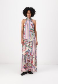 Abito lungo con colletto alto, caratterizzato da un motivo paisley multicolore su uno sfondo crema, con strisce rosa e orlo a strati. Scarpe nere.