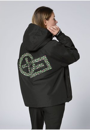 Schwarze Kapuzenjacke mit großem grün-pinkem Leopardenmuster-Logo auf der Rückseite. Verfügt über eine lockere Passform und seitliche Reißverschlüsse.