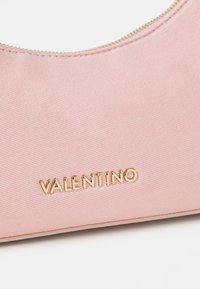 Ροζ υφασμάτινη τσάντα με καμπύλο φερμουάρ, διαθέτοντας το χρυσό λογότυπο "VALENTINO". Η υφή είναι λεία με μια λεπτή διαγώνια υφή.