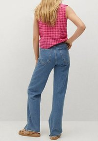 Jean en denim bleu clair avec une coupe droite et un style décontracté ; associé à un haut sans manches à carreaux roses. Design simple, usure minimale.