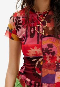 Top de manga corta multicolor con patrones florales en rosa, rojo, naranja y marrón. Fabricado en una tela ligera y texturada con una forma ajustada.