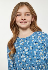 Jasnoniebieska sukienka z kwiatowym wzorem, z stokrotkami i małymi ptakami, wykonana z miękkiej tkaniny, z rozkloszowanym dołem i okrągłym dekoltem.