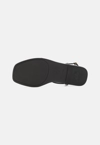 Suola in pelle nera con una texture liscia, forma rettangolare e design piatto. Presenta un marchio impresso e un motivo di presa solido.