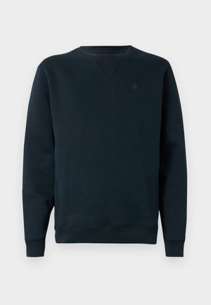 Tengerész stílusú, garbós pulóver, puha anyagból készült, bordázott ujjakkal és derékrésszel, apró logóval a mellkason. Egyszerű, minimalista dizájn.