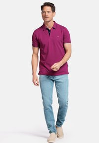 Polo rose avec un col marine contrastant, manches courtes. Assorti à un jean bleu clair et des mocassins beiges.