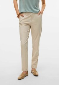 Beige op maat gemaakte broeken met een gladde textuur, voorzien van een rechte pijp en zijzakken. Gecombineerd met lichtbruine instapschoenen.