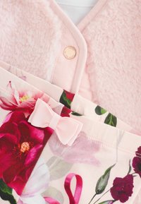 Ziedu raksta audums, ar bagātīgām sarkanām un zaļām krāsām. Mīksts rozā mākslīgā pūkā apkakle ar pogu aizdari. Mazs rozā lentīti akcents auduma malā.