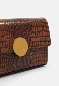 Braune Krokodil-Prägung Leder Clutch mit einem abgerundeten Verschluss aus goldfarbenem Metall und einer glatten Textur. Verfügt über eine Naht entlang der Kanten.