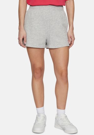 Pantalones cortos de mezcla de algodón gris con una cinturilla elástica, que presentan un ajuste relajado y una textura suave. Llevados con zapatillas blancas y calcetines.