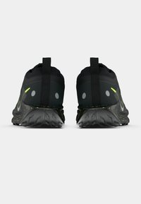 Black running shoes with a textured upper and reflective accents. Features visible Nike logo, padded collar, and a patterned, textured sole.