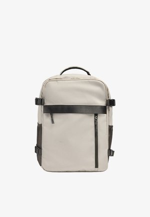 Beżowy prostokątny plecak z czarnym poziomym paskiem, pionową kieszenią na zamek błyskawiczny, bocznymi siateczkowymi kieszeniami i górnym uchwytem.
