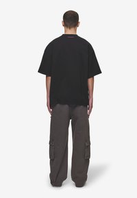 Black oversized t-shirt with a crew neck and short sleeves, paired with loose gray cargo pants featuring side pockets.
