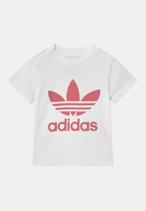 Biała koszulka z krótkim rękawem z dużym czerwonym logo Adidas trefoil i napisem „adidas” na przodzie.