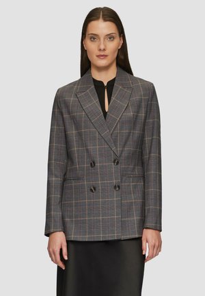 Grijze geruite dubbelknopen blazer met twee voorzakken, zwarte knopen en ingevouwde revers. Gestyled over een zwarte blouse.