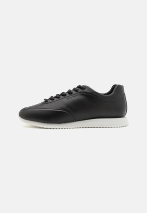 Μαύρο δερμάτινο sneaker με λείο φινίρισμα, λευκή καουτσούκ σόλα, στρογγυλή μύτη και σχέδιο με έξι τρύπες για κορδόνια. Ορατό λογότυπο στο πλάι.