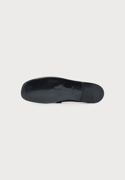 Semelle de chaussure noire vue par le dessous avec des marquages en relief indiquant l'épaisseur et la pointure.