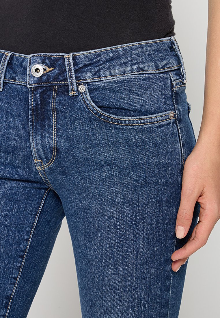 Dunkelblaue Denim-Jeans mit geradem Bein, ausgestattet mit einer Fronttasche, Gürtelschlaufen und einem Metallknopfverschluss. Glatte Textur mit subtilen Verfärbungen.