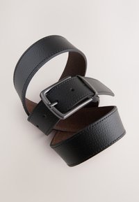 Zwarte leren riem met een gestructureerde afwerking, voorzien van een zilveren metalen gesp en meerdere verstelgaten; gladde binnenkant.