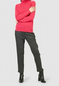 Pull à col roulé fuchsia associé à un pantalon tailleur gris foncé. Bottines noires complètent la tenue. Texture douce et coupe ajustée.