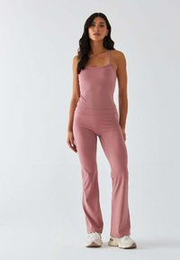 Różowy zestaw sportowy składający się z dopasowanego topu na cienkich ramiączkach oraz rozszerzanych spodni, wykonanych z gładkiej, oddychającej tkaniny.