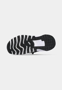 Μαύρη εξωτερική σόλα από καουτσούκ με λευκά στοιχεία, με ανάγλυφο πέλμα για κράτημα και ευκαμψία. Η καμπυλωτή σχεδίαση βελτιώνει την κίνηση.