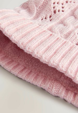 Gestrickte pinke Mütze mit geripptem Bund und Zopfmuster. Weiche Textur mit Lochstrickdetails, die die Atmungsaktivität erhöhen.
