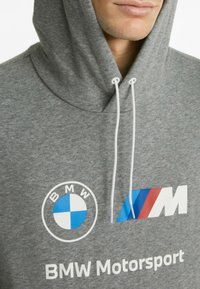 Grijze hoodie met een zachte textuur, voorzien van een witte koord, blauw BMW-logo en de tekst "BMW Motorsport" in het wit.