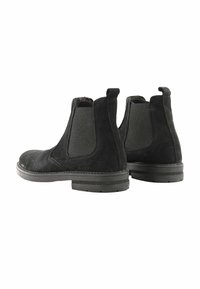 Stivaletti Chelsea in suede neri con pannelli elasticizzati laterali, punte rotonde e suole in gomma nera. Presentano cuciture visibili e dettagli in tessuto texturizzato.