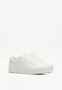 Baskets en cuir blanc avec un bout arrondi, semelle en caoutchouc plate et design minimaliste. Présente des lacets ton sur ton et des détails de couture subtils.