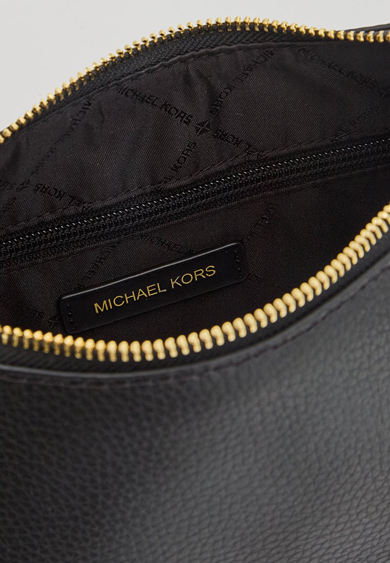 Interno di borsa in pelle nera testurizzata con cerniera dorata. Presenta una fodera in tessuto che mostra chiaramente il nome del marchio "MICHAEL KORS".