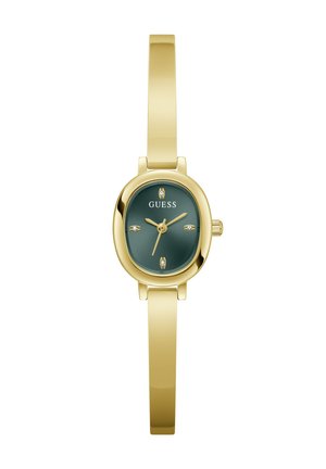 Montre-bracelet à bracelet fin ton or avec cadran ovale vert foncé, aiguilles dorées, quatre petits marqueurs d'heure en cristal et le logo Guess sur le cadran.