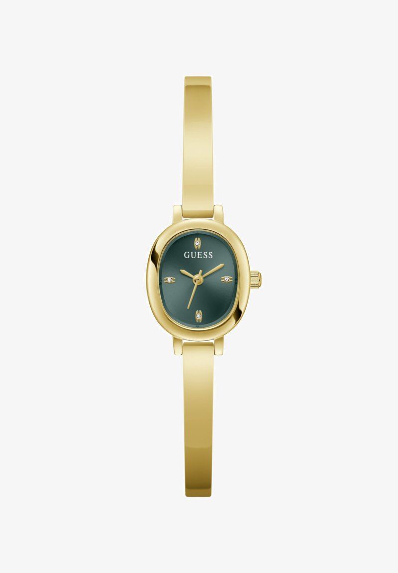 Montre-bracelet à bracelet fin ton or avec cadran ovale vert foncé, aiguilles dorées, quatre petits marqueurs d'heure en cristal et le logo Guess sur le cadran.