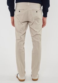 Pantaloni beige a gamba dritta, con due tasche posteriori con bottoni e una finitura pulita. Tessuto in cotone con texture liscia.