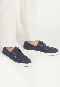 Navy blue casual shoes made of soft material, featuring white stitching, lace-up design, and a white rubber sole.