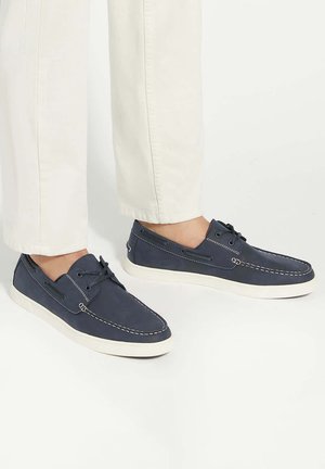 Navy blue casual shoes made of soft material, featuring white stitching, lace-up design, and a white rubber sole.