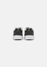 Black athletic shoes with white soles, featuring mesh material, padded collar, and branding on the heel. Smooth and textured surfaces.