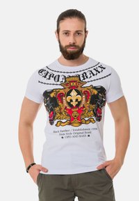 Weißes Baumwoll-T-Shirt mit bunten Grafiken eines Löwen und einer Panther, Kettendesign und Textakzenten. Kurze Ärmel und Rundhalsausschnitt.
