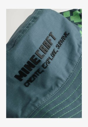 Roheline äärisega müts, tekstuuriga kangast, millel on must reljeefne "MINECRAFT" logo ja tekst "LOO, UURIGE, ÜKS OLEMA". Aktsentõmblus lubjakollases rohelises.