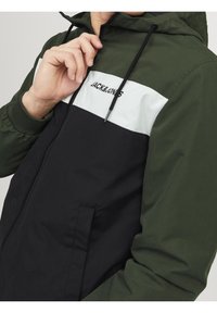 Giacca con cappuccio con chiusura a zip, design a blocchi di colore in verde, bianco e nero, con polsini elasticizzati e tasche laterali. Logo del marchio sul petto.