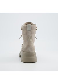 Stivaletto alla caviglia in suede beige con tacco imbottito, punta arrotondata e lace decorativa. La parte posteriore presenta una linguetta in tessuto e un marchio impresso.