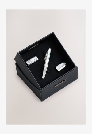 Black gift box containing a silver tie clip and matching cufflinks with smooth, polished rectangular designs on black fabric insert.