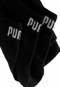 Schwarze Socken mit gerippter Textur und elastischen Bündchen. Mit weißem Text "P U N K", der auf dem oberen Teil gestrickt ist. Vier Paare gestapelt.