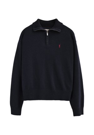 Jersey negro de manga larga con cuello con cremallera hasta la mitad y pequeña figura roja bordada en el pecho izquierdo.