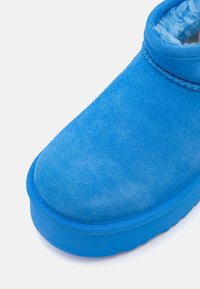 Botte chelsea en daim bleu avec doublure intérieure douce et surface texturée. Bout arrondi et semelle en caoutchouc épaisse, avec un bord cousu.