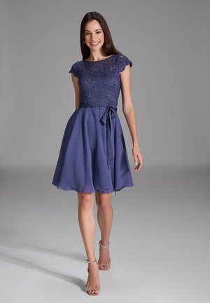 Lila Kleid mit einem Spitzenoberteil und kurzen Ärmeln, fließendem Rock und einem passenden Band in der Taille. Glatter Stoff, knielanges Design.