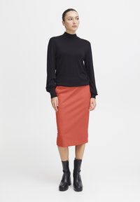 Zwarte lange mouwen turtleneck top gecombineerd met een koraalkleurige kokerrok tot de knie en zwarte enkelboots, met een gladde textuur en een minimalistisch ontwerp.