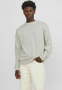 Light gray crewneck sweater with ribbed cuffs and hem, paired with off-white jeans. Soft, textured fabric with a relaxed fit.